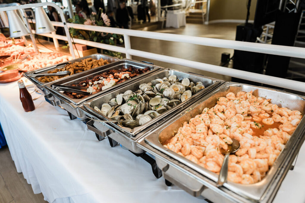 Buffet selection of seafood dishes including shrimp, clams, and calamari served in stainless steel trays during an engagement celebration at The Armory NJ Restaurant in Perth Amboy, captured by Alex Kaplan Photography.