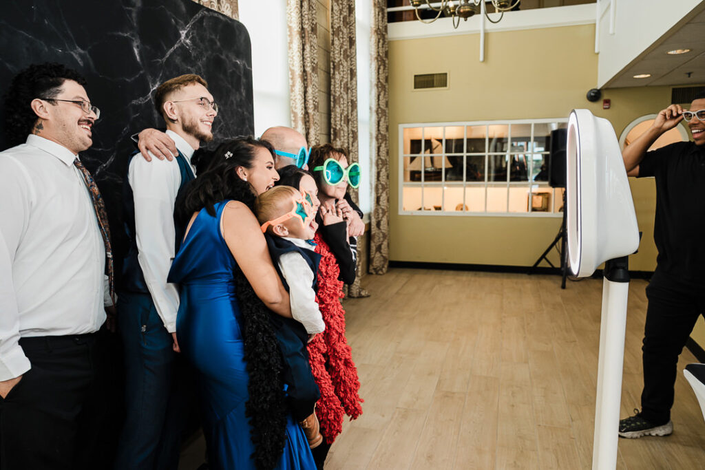 Guests enjoying the photo booth with playful props and oversized sunglasses during an engagement celebration at The Armory NJ Restaurant in Perth Amboy, captured by Alex Kaplan Photography.