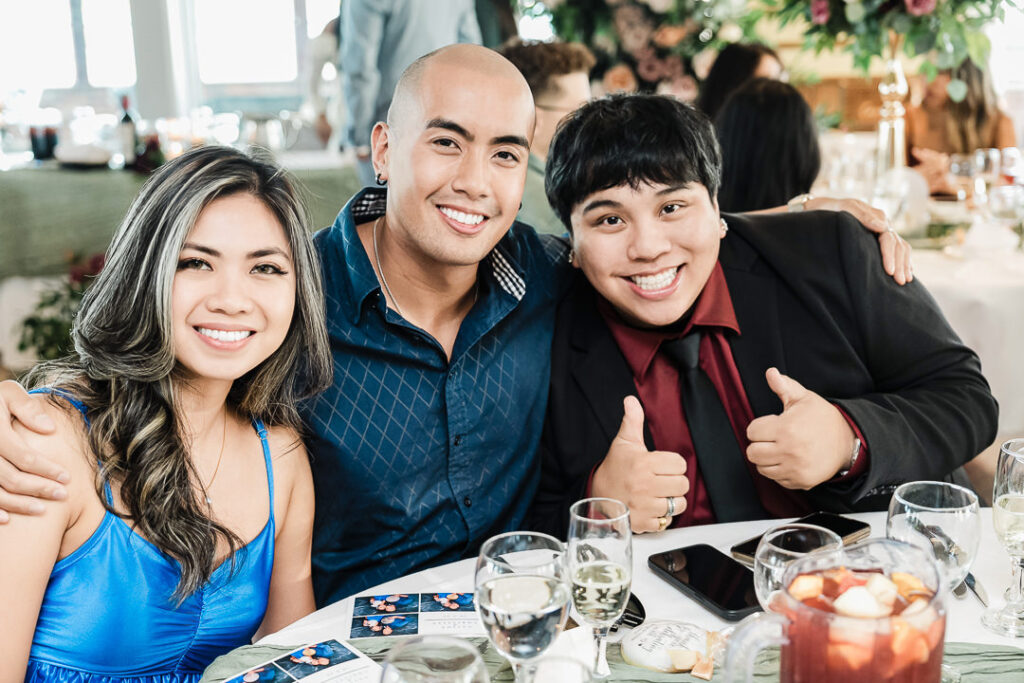 Friends smiling and posing together at a beautifully decorated reception table during an engagement party at The Armory NJ Restaurant in Perth Amboy, photographed by Alex Kaplan Photography.
