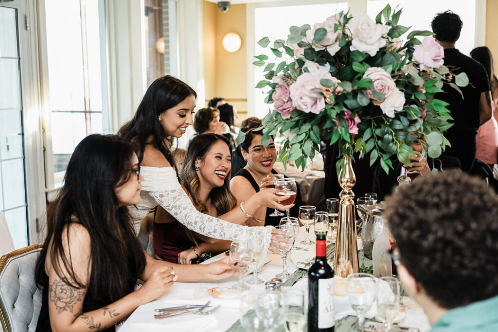 Guests laughing and raising glasses in a joyful toast during an engagement celebration at The Armory NJ Restaurant in Perth Amboy, captured by Alex Kaplan Photography.