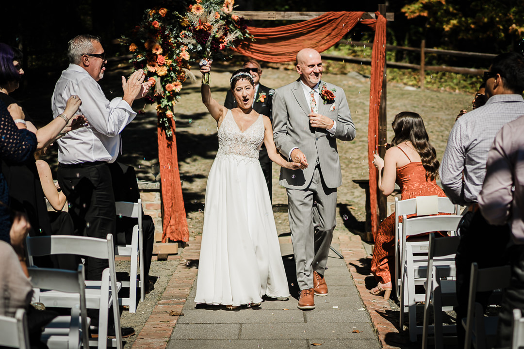 Bride and groom walk down the aisle at their outdoor fall ceremony at Mohawk House in Sparta NJ, captured by Alex Kaplan Weddings.
