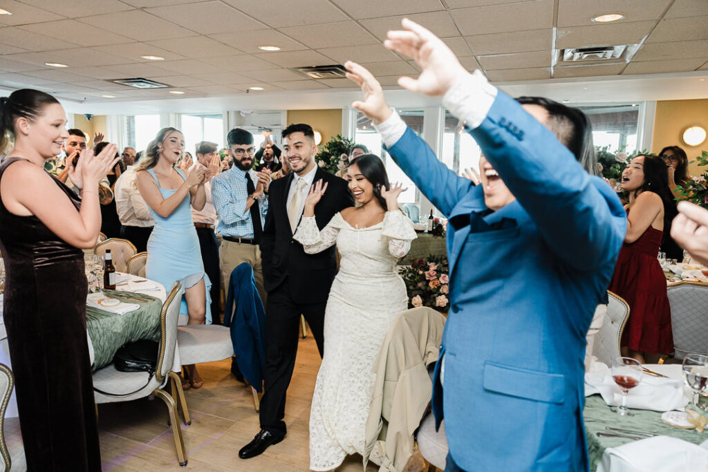 Guests cheering and clapping as the couple joins the dance floor during an energetic engagement celebration at The Armory NJ Restaurant in Perth Amboy, photographed by Alex Kaplan Photography.