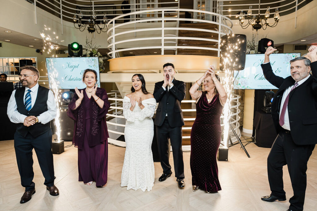 Couple celebrating with family during grand entrance surrounded by sparklers at The Armory NJ Restaurant in Perth Amboy, photographed by Alex Kaplan Photography.