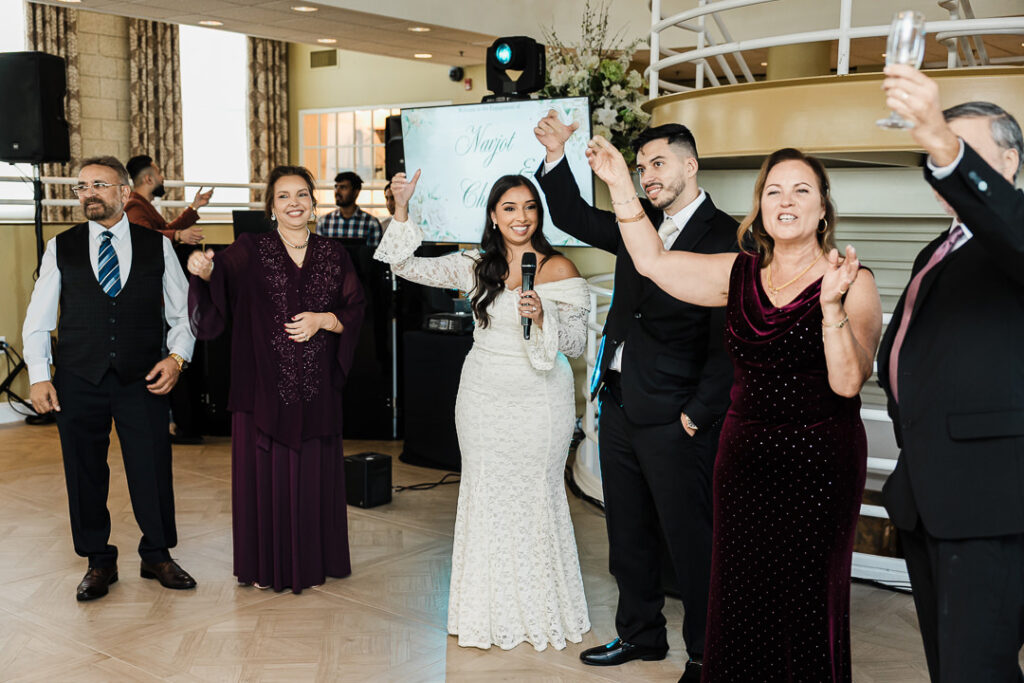 Bride and groom celebrating with family during a joyful wedding toast at The Armory NJ Restaurant in Perth Amboy, photographed by Alex Kaplan Photography.