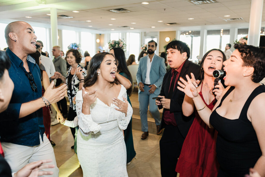 Bride singing and dancing with guests during lively wedding reception at The Armory NJ Restaurant in Perth Amboy, photographed by Alex Kaplan Photography.