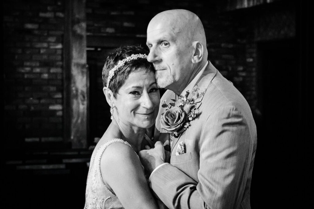 Emotional moment during the first dance as the couple holds each other close in the candlelit Mohawk House reception space.