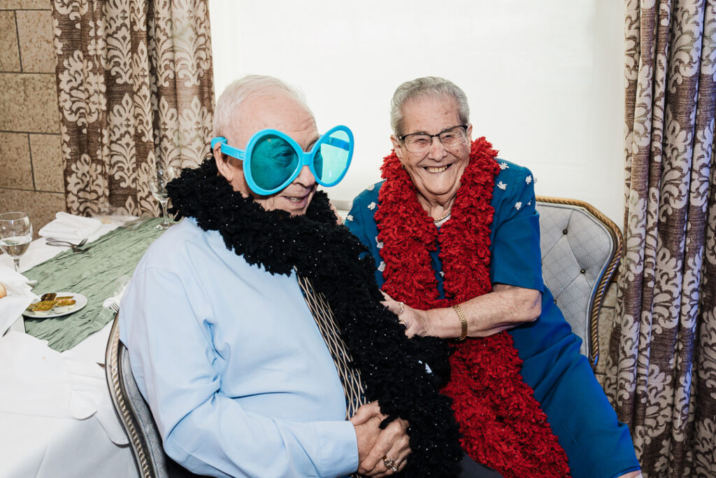 Guests sharing a joyful moment with fun props during wedding reception at The Armory NJ Restaurant in Perth Amboy, photographed by Alex Kaplan Photography.