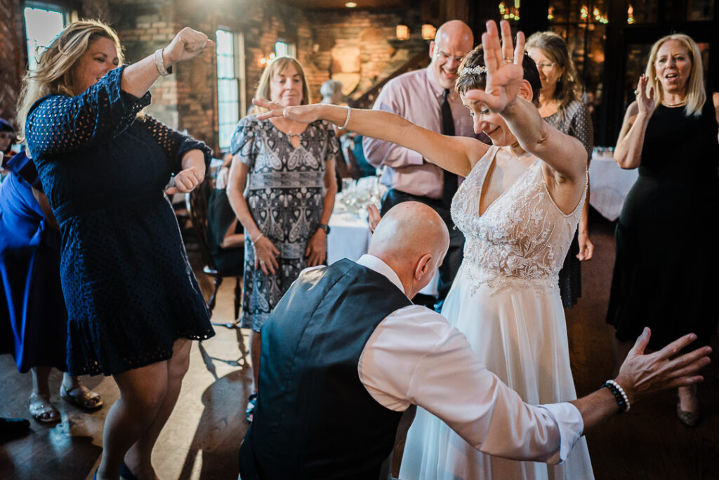 Guests dancing joyfully with the couple on the dance floor during Mohawk House wedding reception.