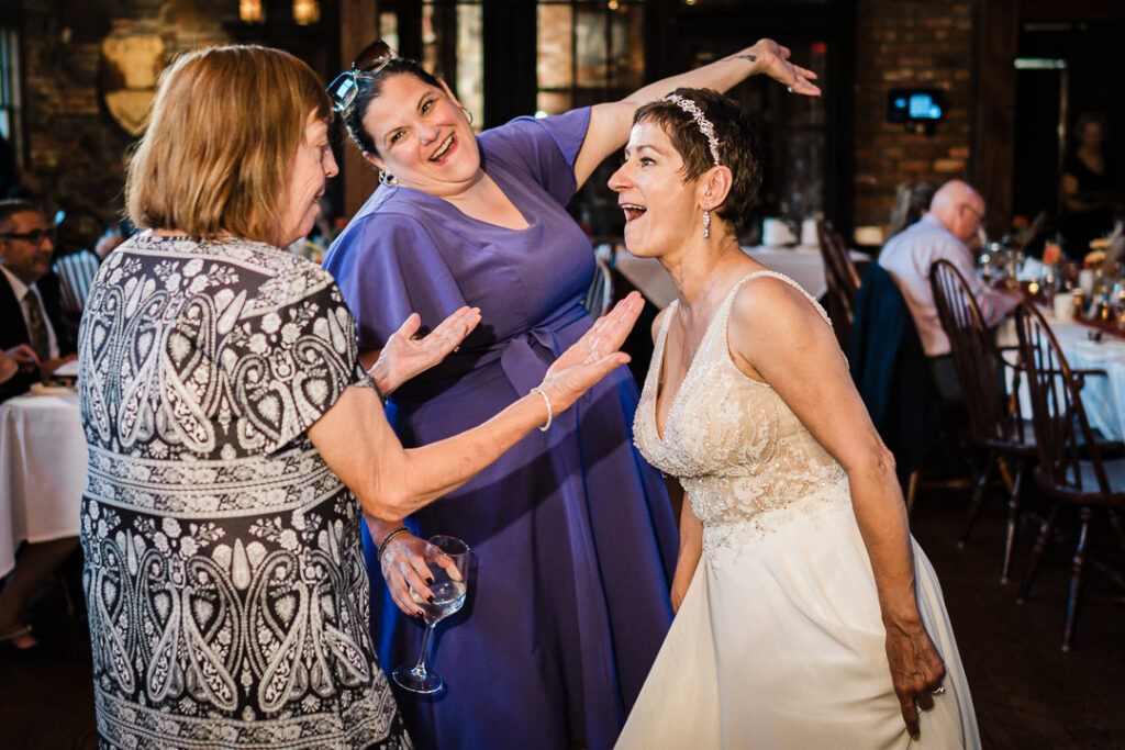 Bride laughing and dancing with guests during Mohawk House wedding celebration.