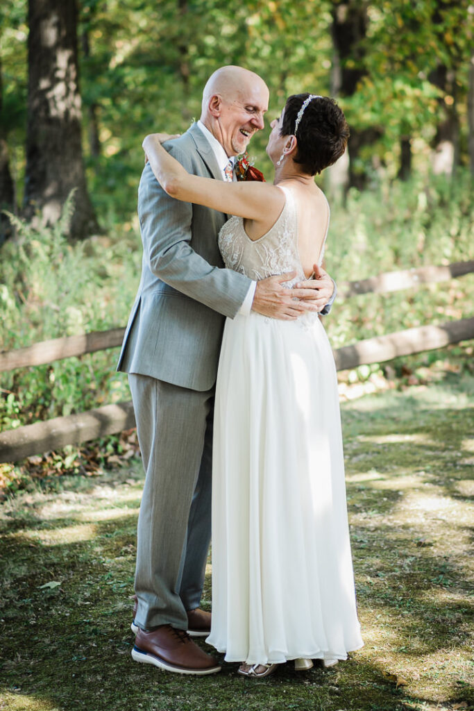 Bride and groom embracing after their first look surrounded by trees and wooden fencing at Mohawk House.