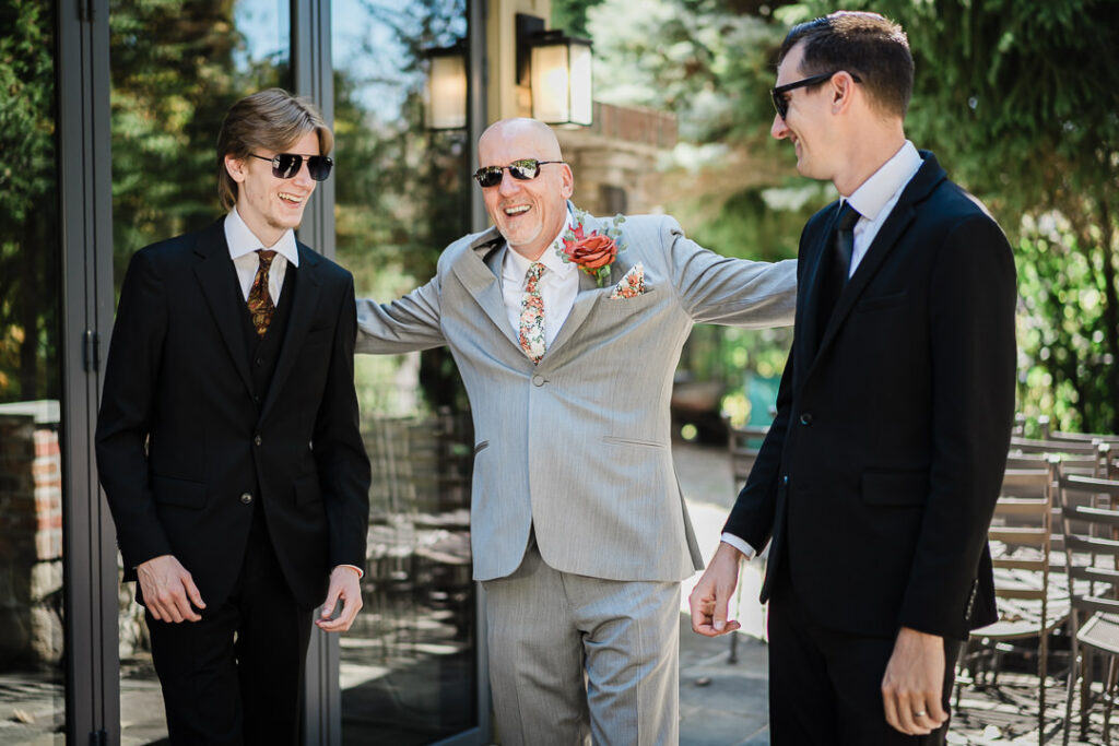 Groom sharing a lighthearted moment adjusting boutonniere with his sons before the ceremony at Mohawk House.