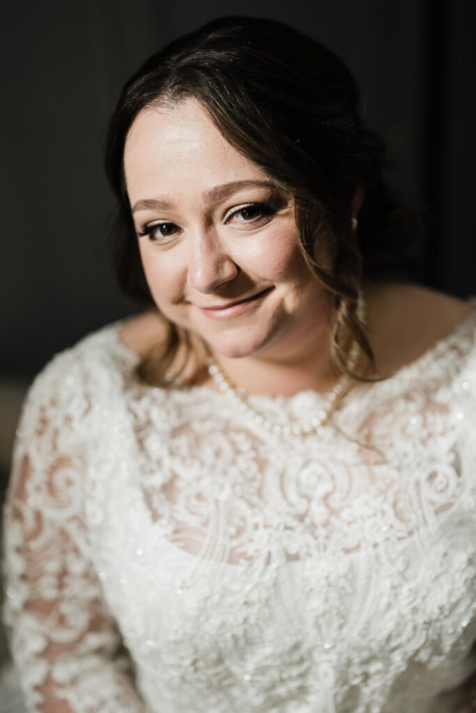 Close-up bridal portrait of bride in lace wedding dress with pearls.