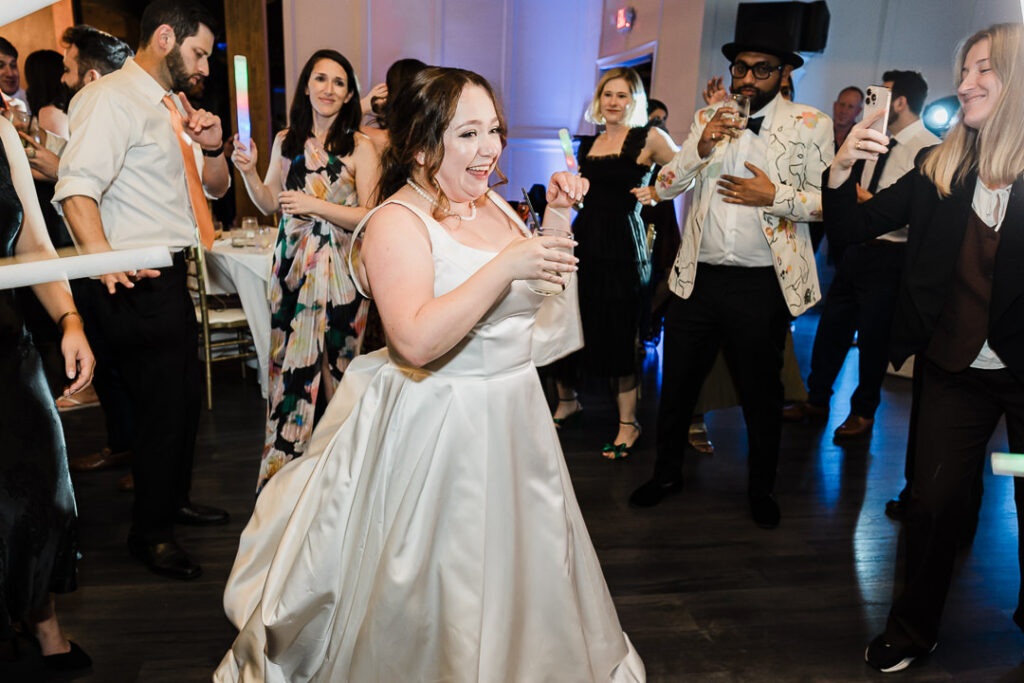 Bride dancing with glow sticks surrounded by wedding guests.