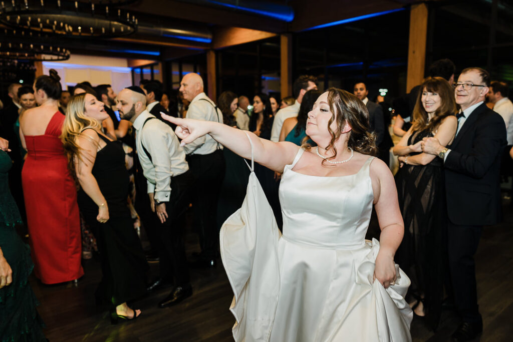 Bride in elegant satin ballgown dancing at wedding reception.