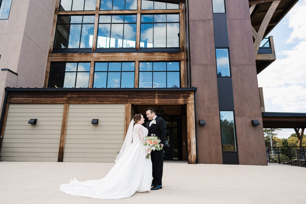 Newlyweds posing in front of The View venue entrance showing modern architecture