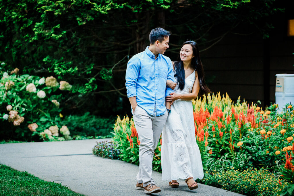 Couple walking past orange and yellow flowers at Deep Cut Gardens engagement shoot