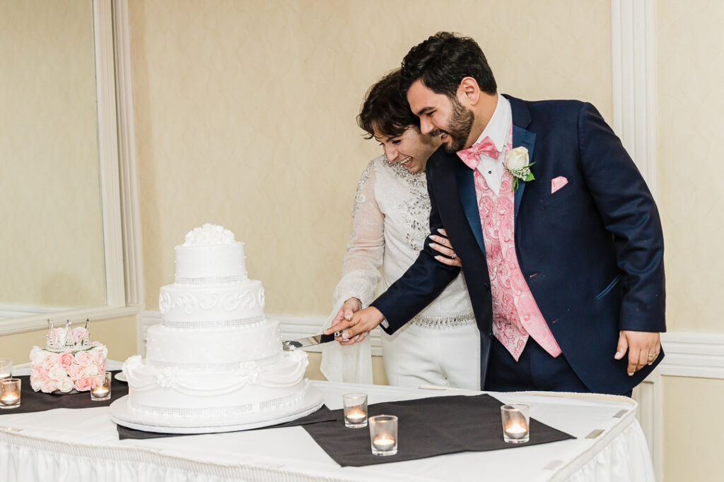 Couple cutting four-tier white wedding cake together Cortlandt Colonial reception Hudson Valley wedding
