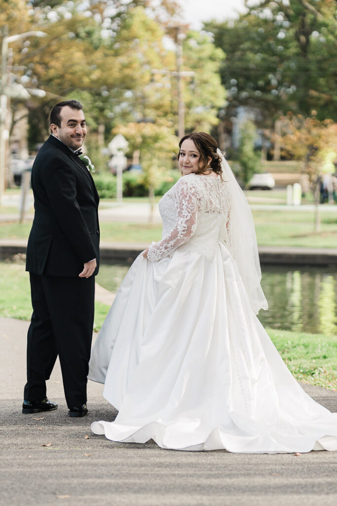Bride and groom looking at each other by pond at Lincoln Park during fall.