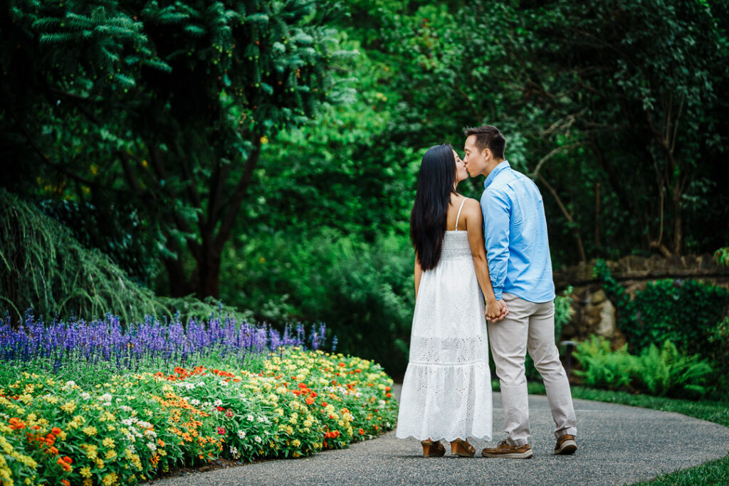 Engaged couple walking hand in hand through Deep Cut Gardens pathways