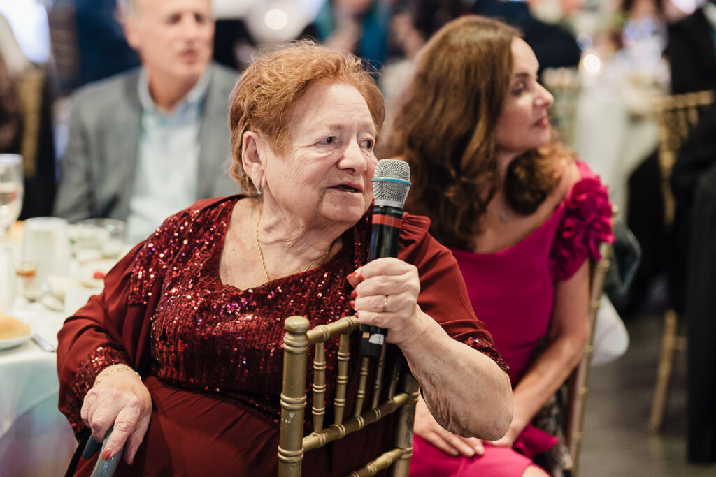 Grandmother in burgundy dress giving heartfelt wedding speech.