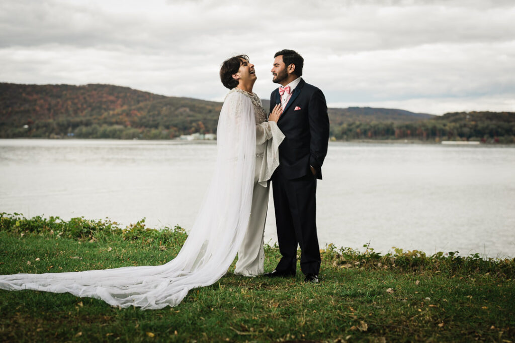 Candid moment of couple laughing together by Hudson River with fall scenery, Peekskill wedding photography