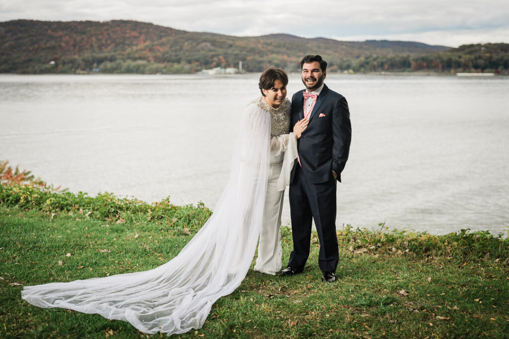 Couple by lakeside with autumn foliage and flowing veil, Hudson Valley fall wedding photography
