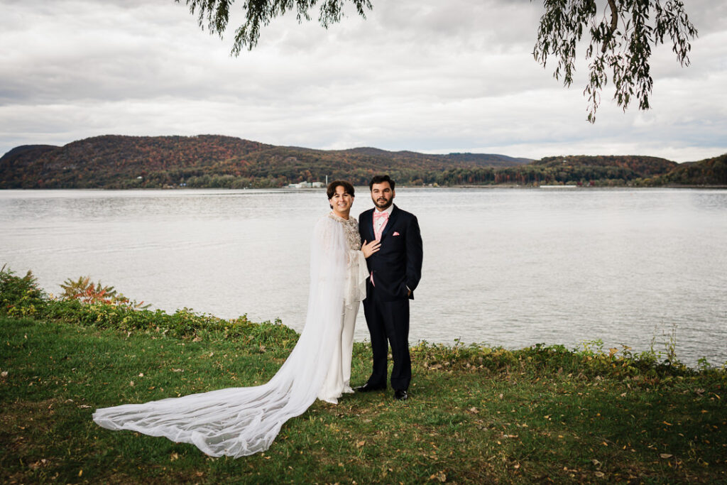 Couple standing beneath weeping willow by Hudson River with long veil, romantic fall wedding Peekskill NY
