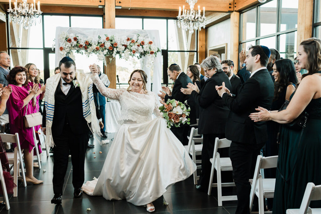 Newlyweds walk down the aisle as guests celebrate at wedding ceremony.
