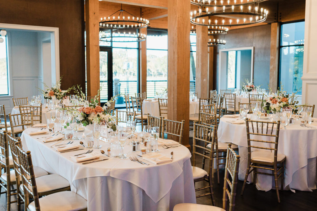 Reception room with gold chiavari chairs and coral centerpieces.