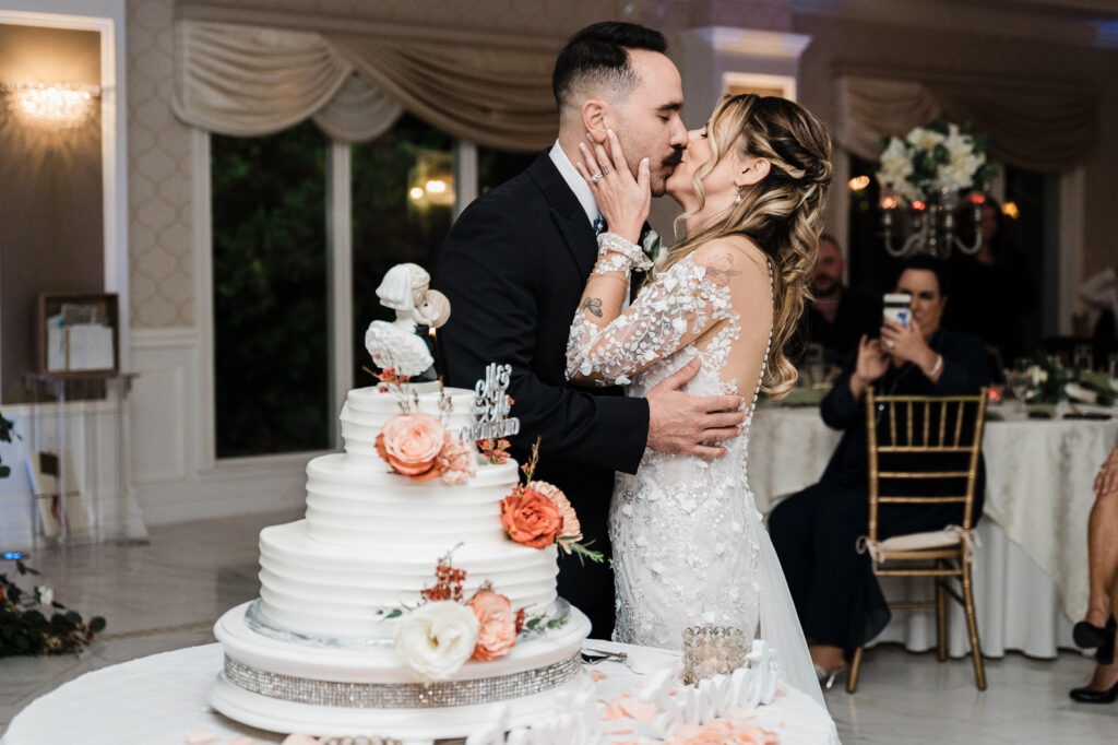 Bride and groom kissing during cake cutting at The English Manor wedding reception