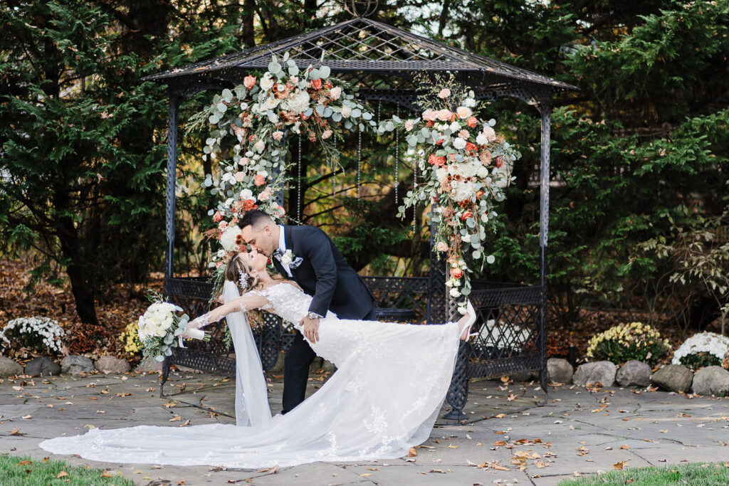 Romantic dip and kiss under floral gazebo at The English Manor fall wedding