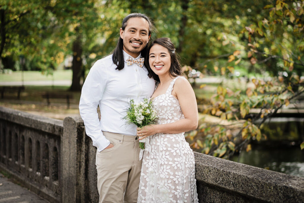 Happy newlyweds posing together by bridge with fall scenery in NJ