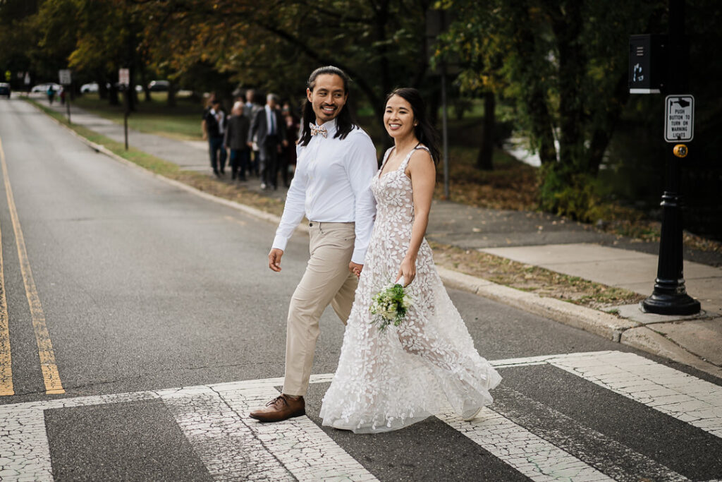 Newlyweds walking hand in hand on tree-lined street after wedding in NJ