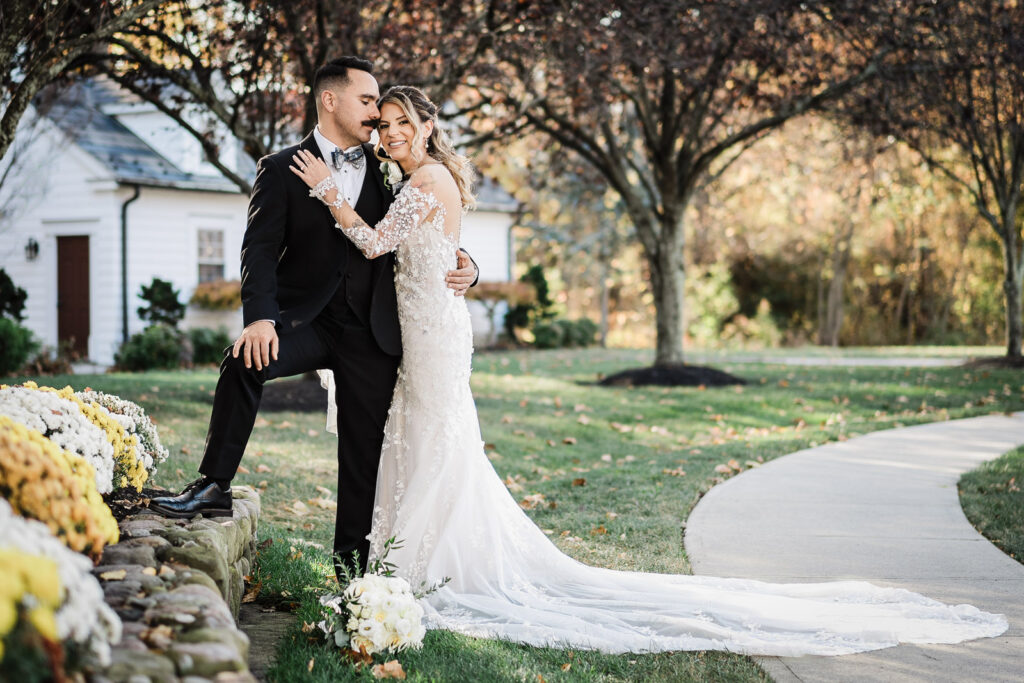 Bride and groom romantic portrait with yellow mums and stone wall at The English Manor fall wedding