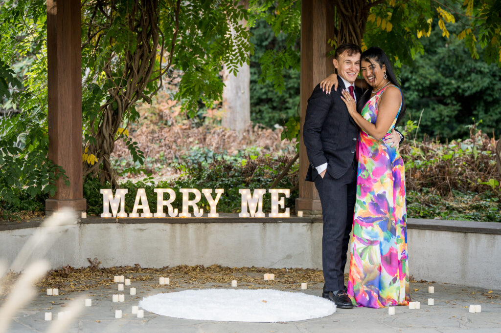 Newly engaged couple showing engagement ring during fall botanical garden portrait session
