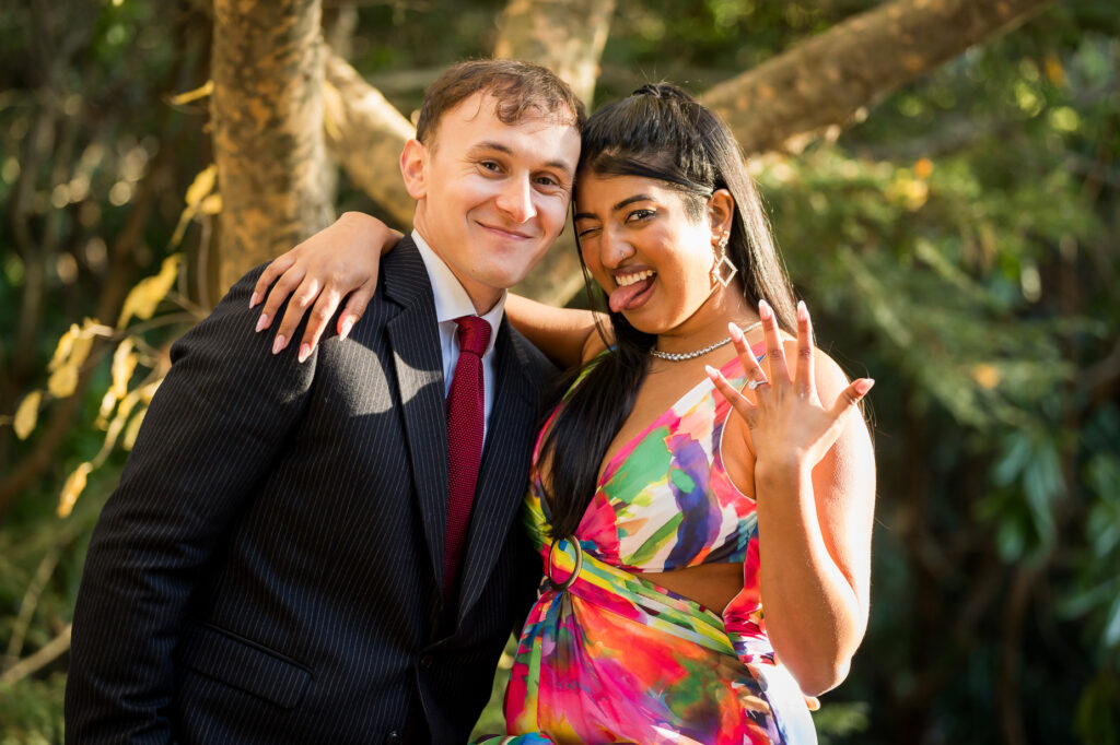 Engaged couple walking hand in hand along garden path with colorful autumn leaves