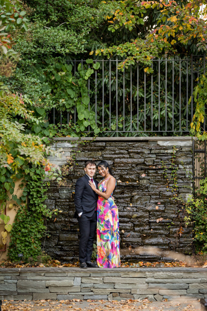 Couple walking through vibrant fall foliage during botanical garden engagement session