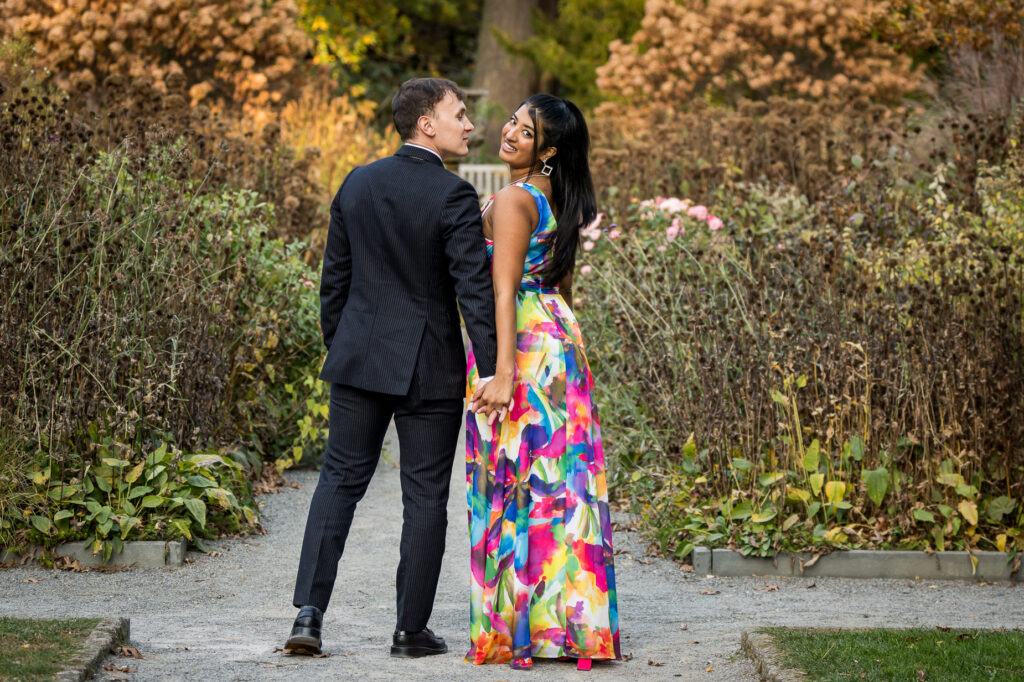Engaged couple portrait against stone architectural wall at botanical garden during fall