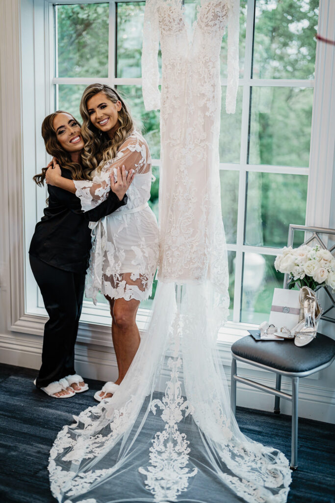 Bride embracing bridesmaid during getting ready at The Legacy Castle Pompton Plains by Alex Kaplan
