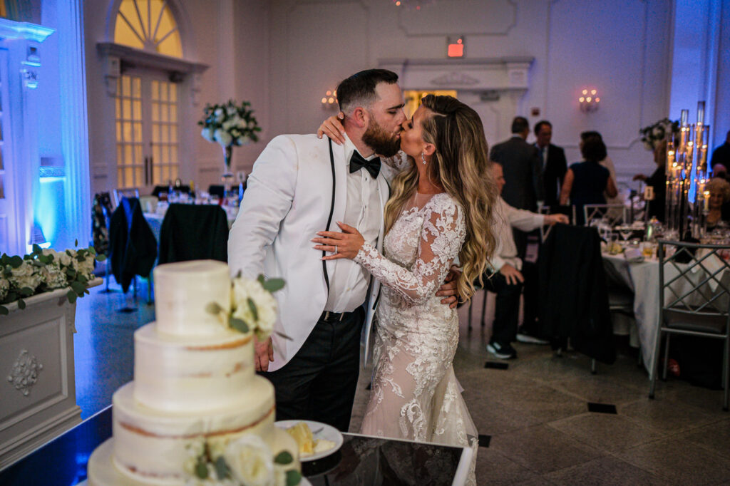 Couple kissing during cake cutting at The Legacy Castle wedding by Alex Kaplan