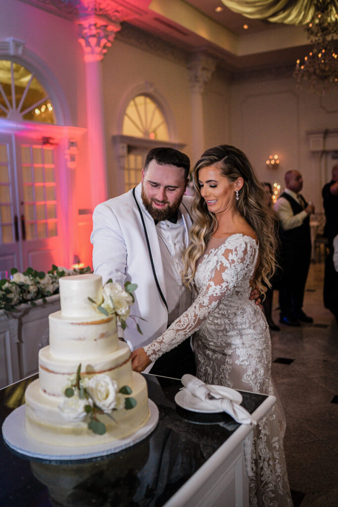 Semi-naked wedding cake with white roses and eucalyptus at Legacy Castle by Alex Kaplan Photography