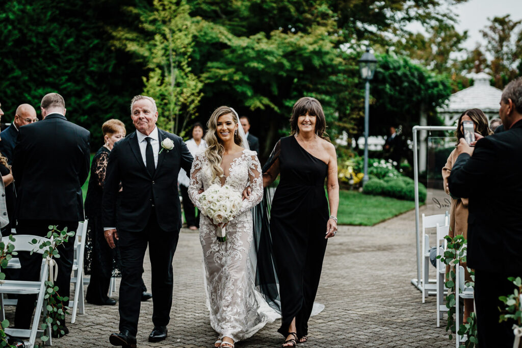 Bride walking down aisle with parents at Legacy Castle outdoor ceremony in Pompton Plains NJ photographed by Alex Kaplan