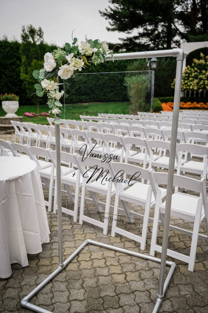 Ceremony welcome sign with floral arrangement at Legacy Castle Pompton Plains by Alex Kaplan Photography