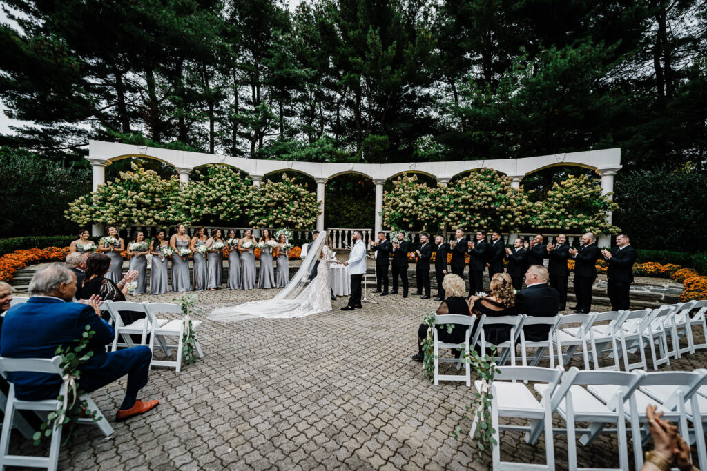 Wide angle ceremony view with wedding party at Legacy Castle with hydrangea backdrop by Alex Kaplan