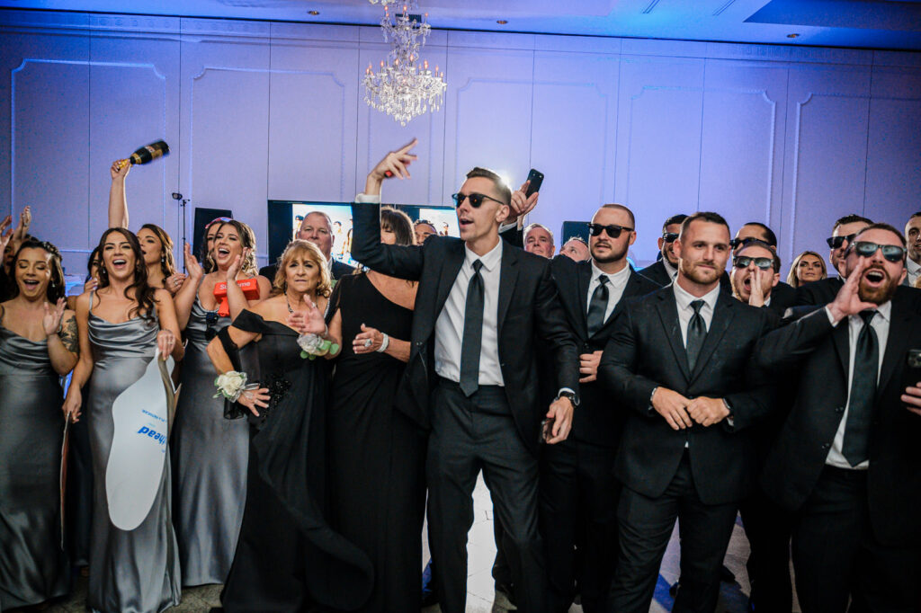 Couple's grand entrance with arms raised at Legacy Castle Pompton Plains wedding by Alex Kaplan Photography