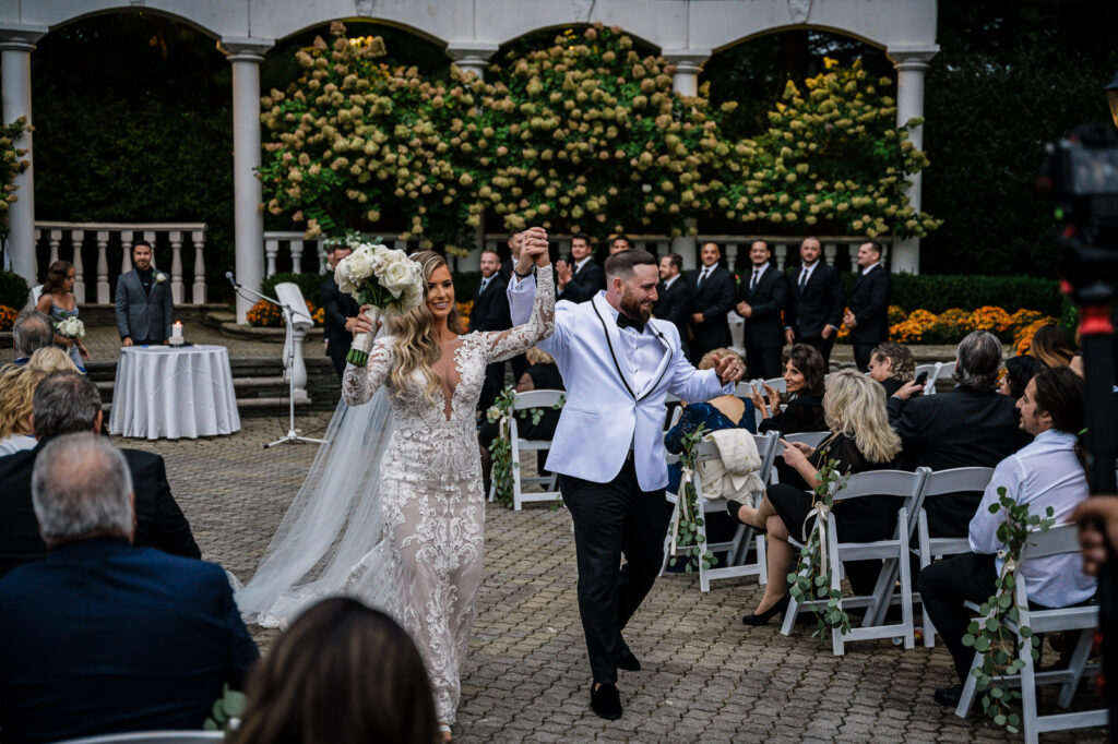 Newlyweds celebrating during recessional at Legacy Castle Pompton Plains NJ wedding by Alex Kaplan