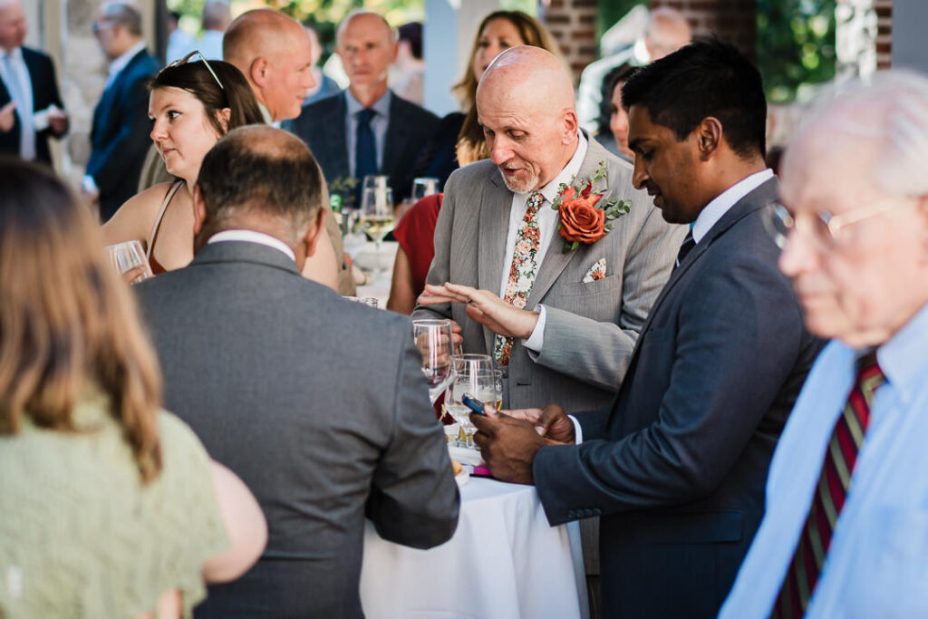 Groom mingles with guests during cocktail hour at Mohawk House fall wedding in Sparta New Jersey by Alex Kaplan Photography