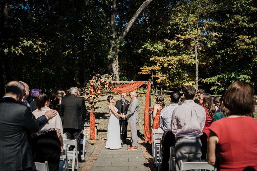 Wide shot of outdoor fall ceremony under trees at Mohawk House venue in Sparta NJ photographed by Alex Kaplan