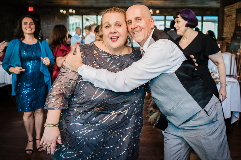 Groom hugs guest on dance floor at Mohawk House fall wedding reception in Sparta NJ by Alex Kaplan Photography