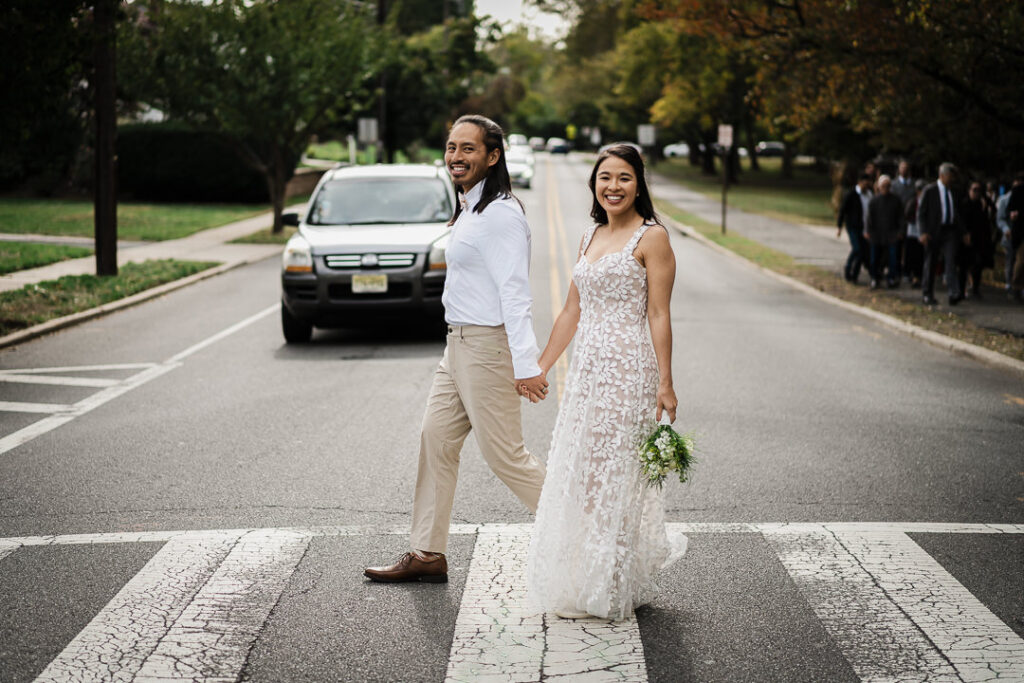 Newlyweds crossing street together on their wedding day in NJ